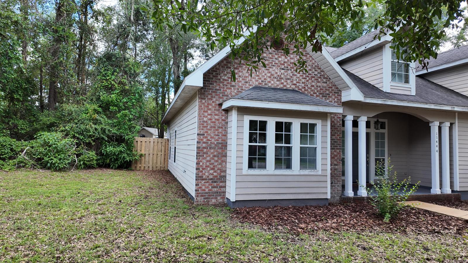 A brick and siding house exterior with a front porch and a grassy side yard — 11444 NW 18th Lane, Gainesville FL 32606, GAINESVILLE, FL