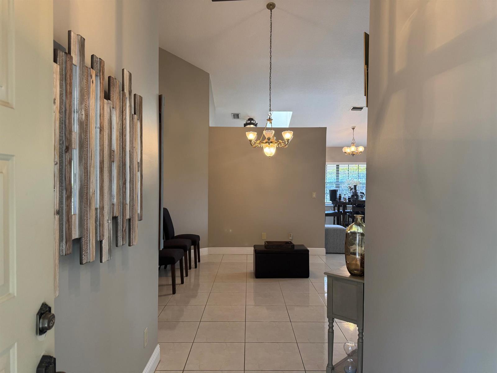 An entryway with light tile flooring leads into a living area featuring a chandelier — 6803 Bitterbush Place, Boynton Beach FL 33472, BOYNTON BEACH, FL
