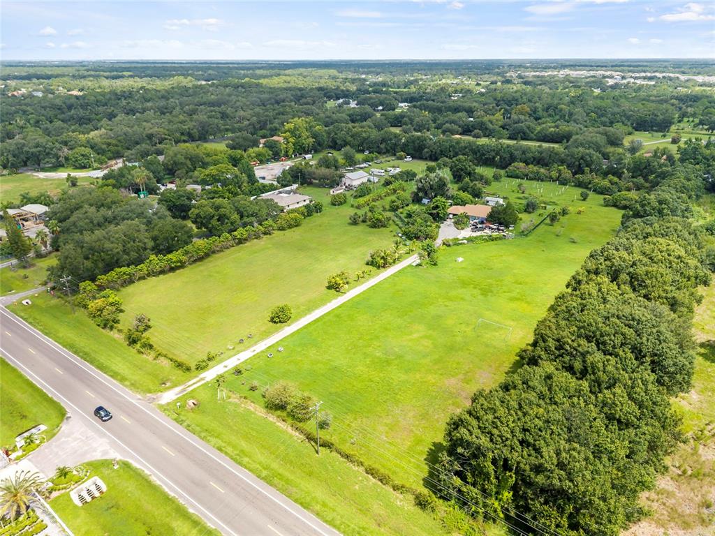 An aerial view shows a large grassy lot with a house and driveway near a road — 16305 E STATE ROAD 64, BRADENTON, FL