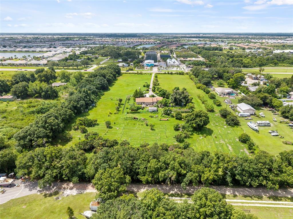 An aerial view shows a house situated on a large, grassy lot with trees — 16305 E STATE ROAD 64, BRADENTON, FL