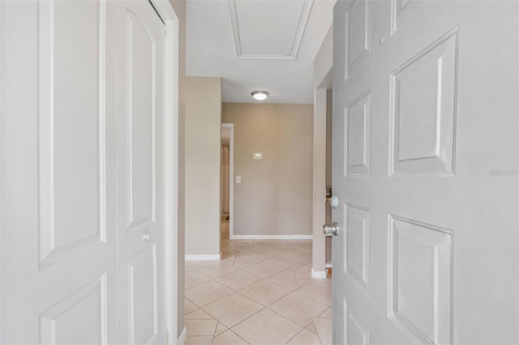 An entryway features a white door, tiled flooring, and a hallway leading to another room — 1109 SOMERSET CIRCLE S, DUNEDIN, FL
