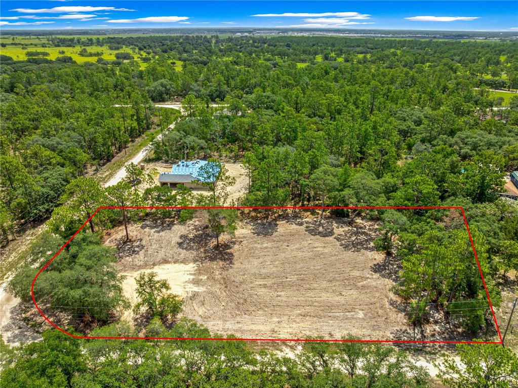 An aerial view shows a cleared rectangular lot surrounded by trees near a house — TBD SW 122 AVENUE, DUNNELLON, FL