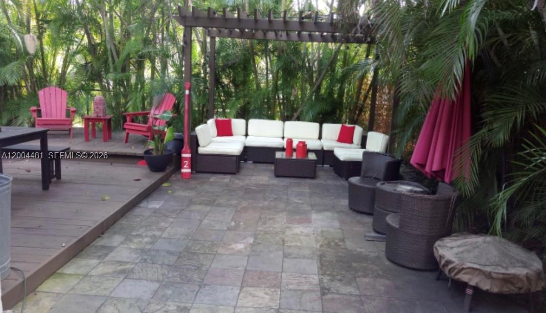 A stone patio features a pergola, modular outdoor seating, and red accent chairs — 5718 SW 48th St, South Miami FL 33155, SOUTH MIAMI, FL