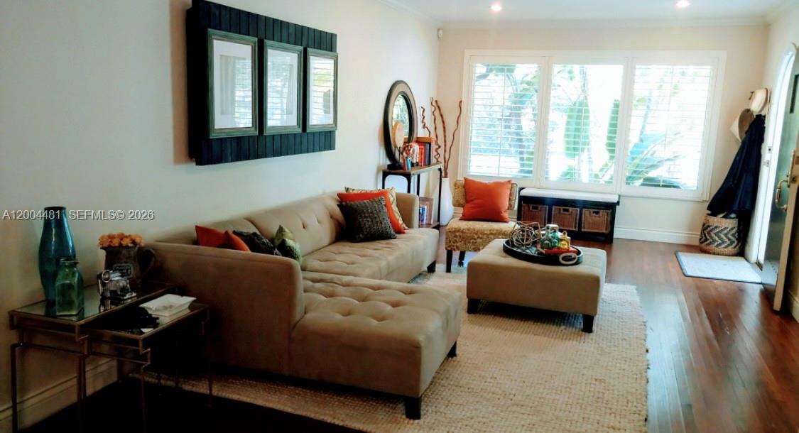 A living room features a beige sectional sofa, a matching ottoman, and large windows — 5718 SW 48th St, South Miami FL 33155, SOUTH MIAMI, FL