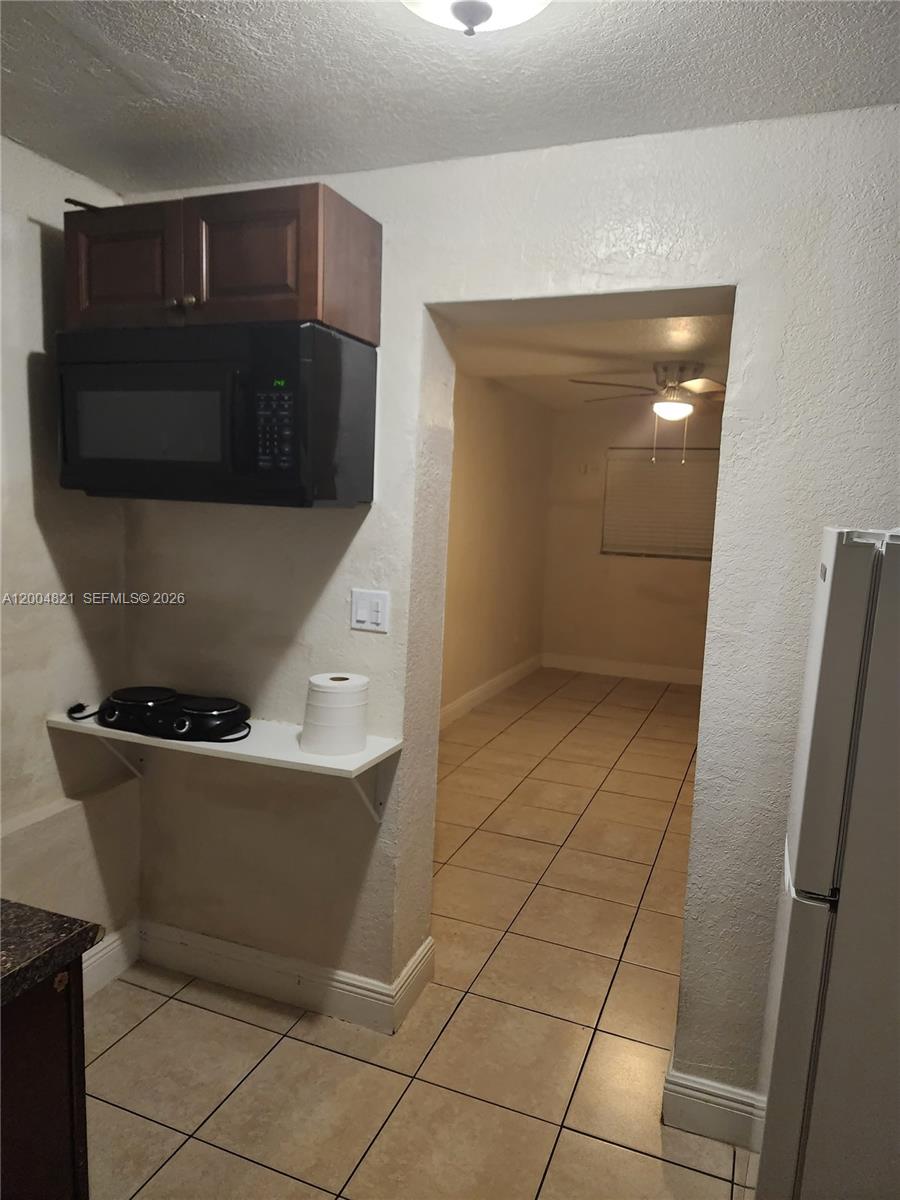A small kitchen area features a microwave, upper cabinet, and a shelf with burners — 6421 SW 18th St # 1, Miramar FL 33023, MIRAMAR, FL
