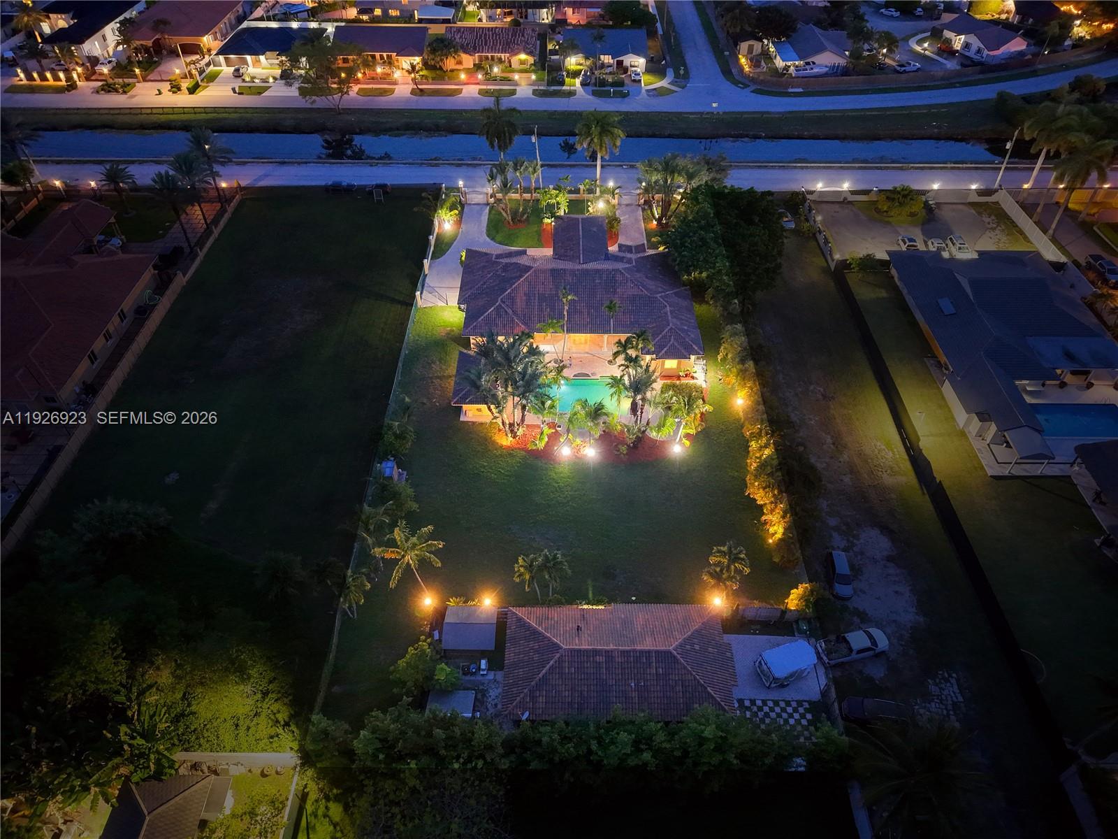 An aerial night view of a residential property featuring a house, pool, and detached garage — 3001 SW 132nd Ave, Miami FL 33175, MIAMI, FL