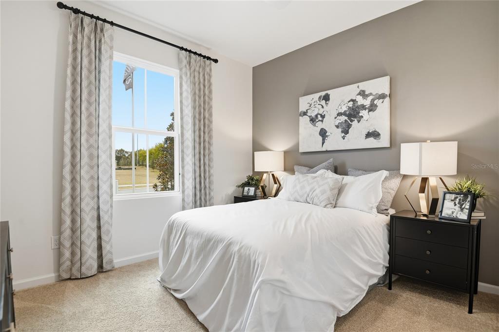 A bedroom features a bed with white bedding, two black nightstands, and a world map — 3236 WAGHORN DRIVE, TAVARES, FL