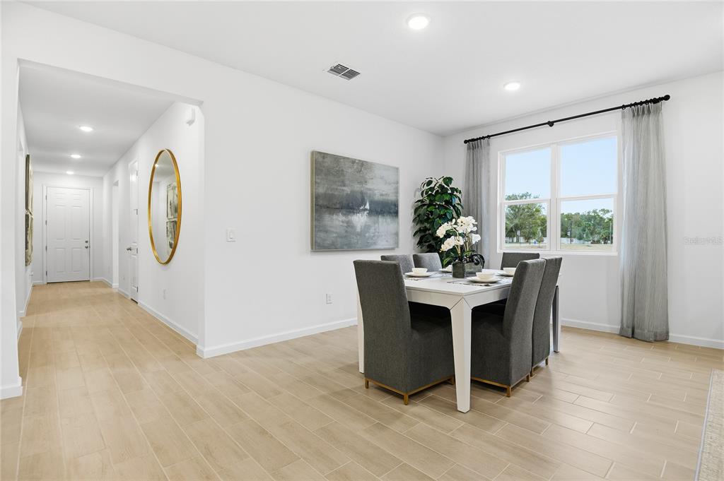A dining room with a white table, gray chairs, and light wood-look tile flooring — 3236 WAGHORN DRIVE, TAVARES, FL