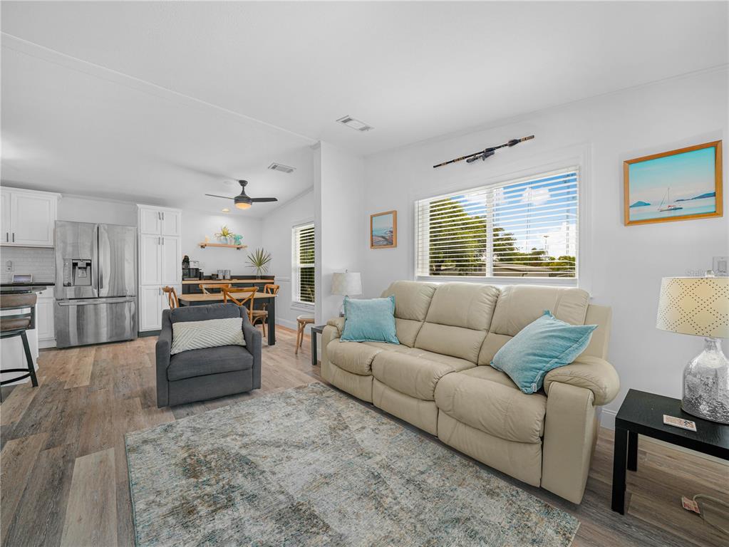 A living room with a beige sofa, gray armchair, area rug, and an open kitchen — 24 SILVERSIDES STREET, LAKE WALES, FL