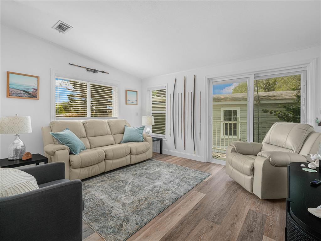 A living room features a beige sofa, a recliner, a gray area rug, and wood flooring — 24 SILVERSIDES STREET, LAKE WALES, FL