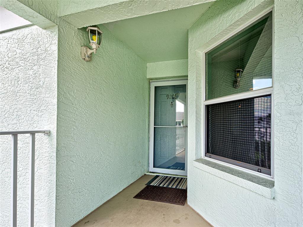A covered entryway features light green stucco walls, a screen door, and a single window — 5725 GREENWOOD AVENUE UNIT 9201, NORTH PORT, FL