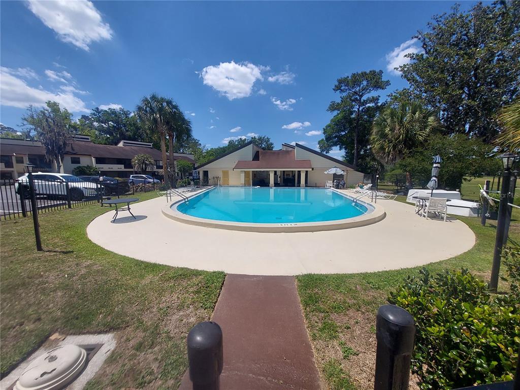 An outdoor swimming pool with a surrounding deck and a clubhouse in the background — 3535 E FORT KING STREET UNIT 160, OCALA, FL