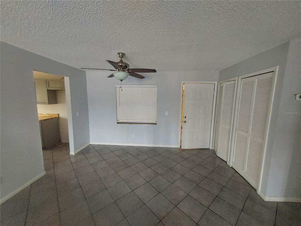 A room with light blue walls, gray tile flooring, a ceiling fan, and white louvered closets — 3535 E FORT KING STREET UNIT 160, OCALA, FL