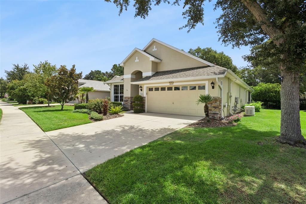 A single-story house with a beige stucco exterior, stone accents, and a two-car garage — 8270 BRIDGEPORT BAY CIRCLE, MOUNT DORA, FL
