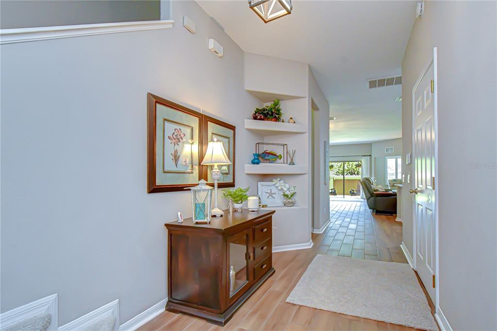 A foyer features a wooden console table, built-in wall niches, and a view into the living area — 2938 LOCHCARRON DRIVE, LAND O LAKES, FL