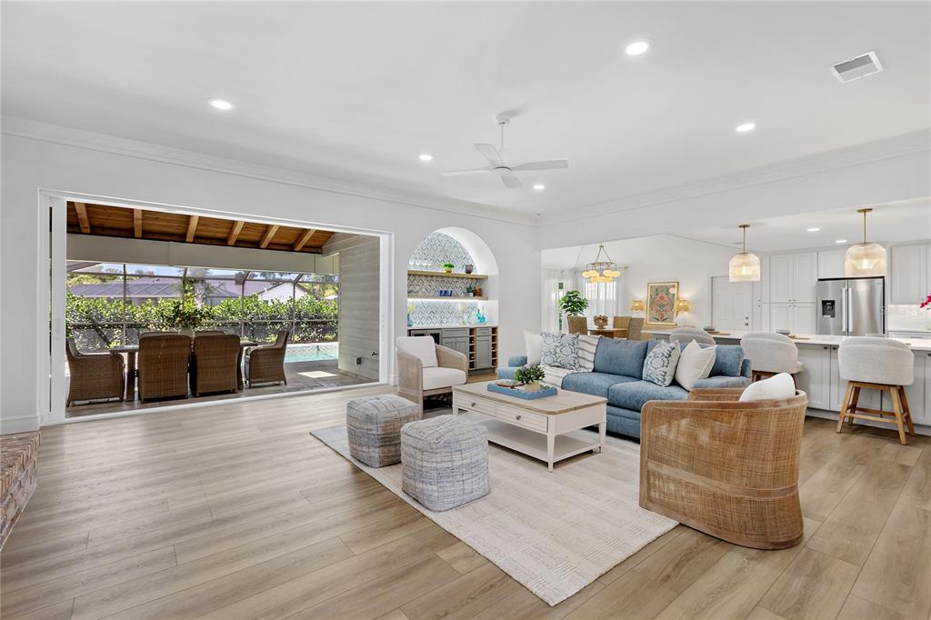 This open-concept living room features a blue sofa, a kitchen island, and sliding glass doors — 4908 TAYWATER DELL, SARASOTA, FL