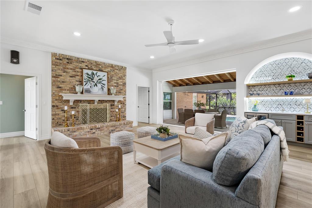 A living room features a brick fireplace, a wet bar, and sliding doors to a patio — 4908 TAYWATER DELL, SARASOTA, FL