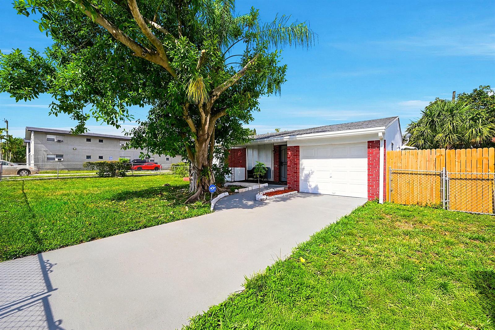A single-story house with a white garage, red brick accents, and a large front tree — 1716 N 25th Avenue, Hollywood FL 33020, HOLLYWOOD, FL