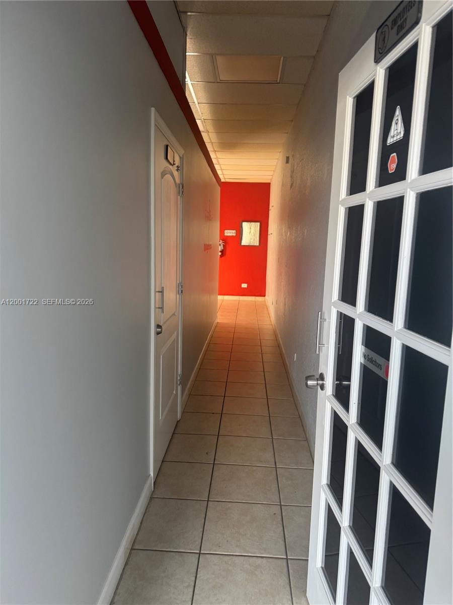 A narrow hallway features light-colored tile flooring, gray walls, and a red accent wall — 700 Palm Ave # 702, Hialeah FL 33010, HIALEAH, FL