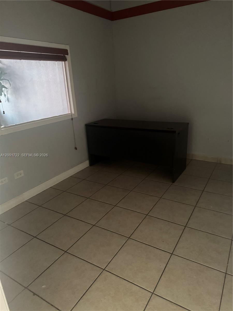 A room with light gray walls, a dark desk, and beige tiled flooring — 700 Palm Ave # 702, Hialeah FL 33010, HIALEAH, FL