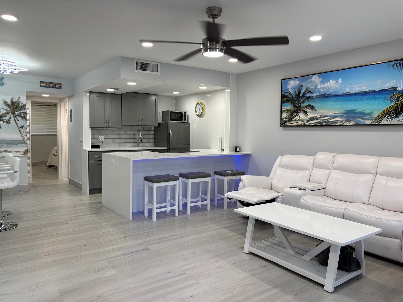 A modern open-concept living area features a kitchen with gray cabinets and a white island — 2565 S Ocean Boulevard # 1230, Palm Beach FL 33480, PALM BEACH, FL