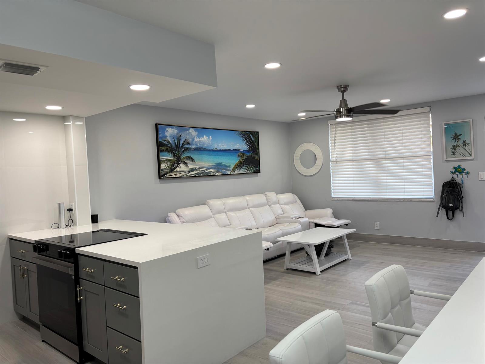 A modern kitchen and living area with gray cabinets, white countertops, and a white sofa — 2565 S Ocean Boulevard # 1230, Palm Beach FL 33480, PALM BEACH, FL