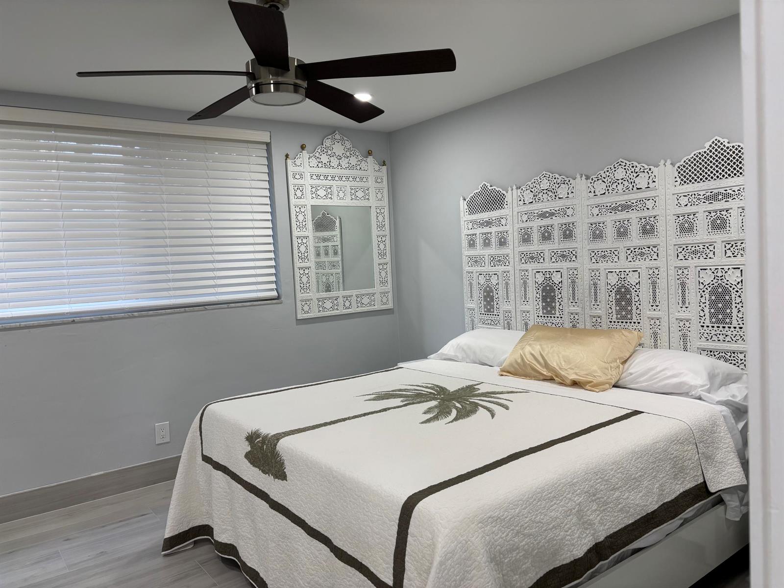 A bedroom features a white carved headboard, a palm tree quilt, and a ceiling fan — 2565 S Ocean Boulevard # 1230, Palm Beach FL 33480, PALM BEACH, FL