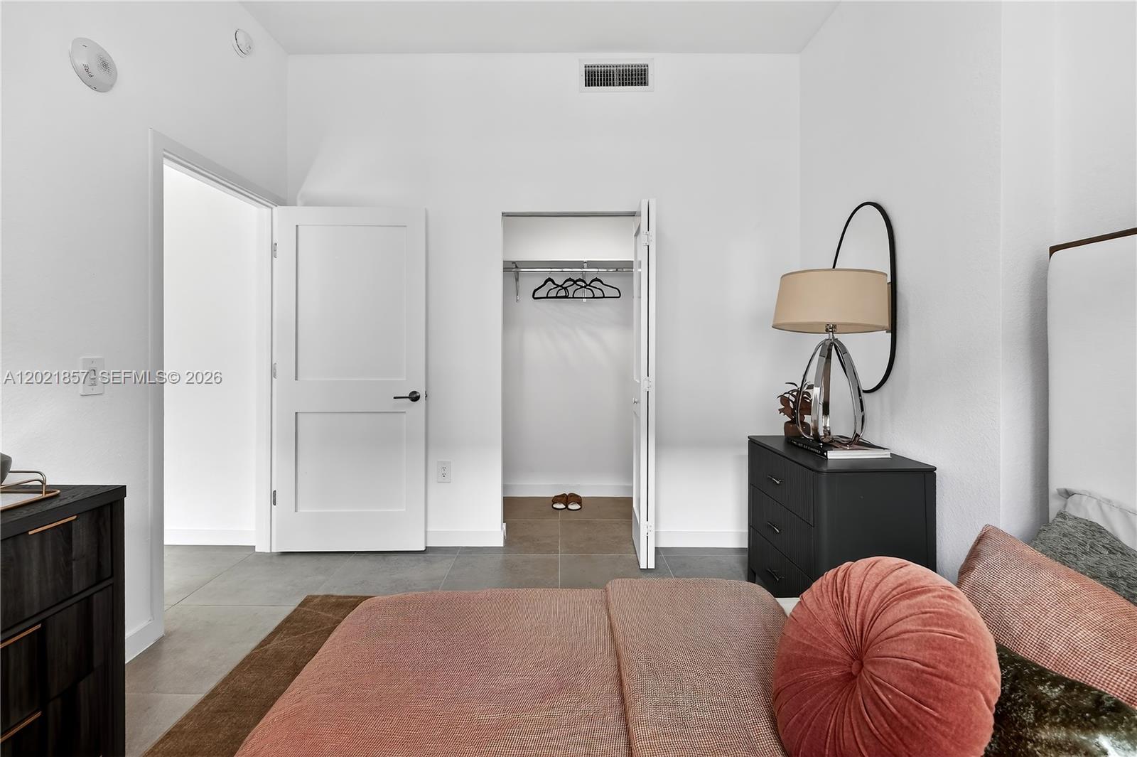 A bedroom features a bed, a dresser with a lamp, and an open closet door — 2001 Van Buren St # 502, Hollywood FL 33020, HOLLYWOOD, FL
