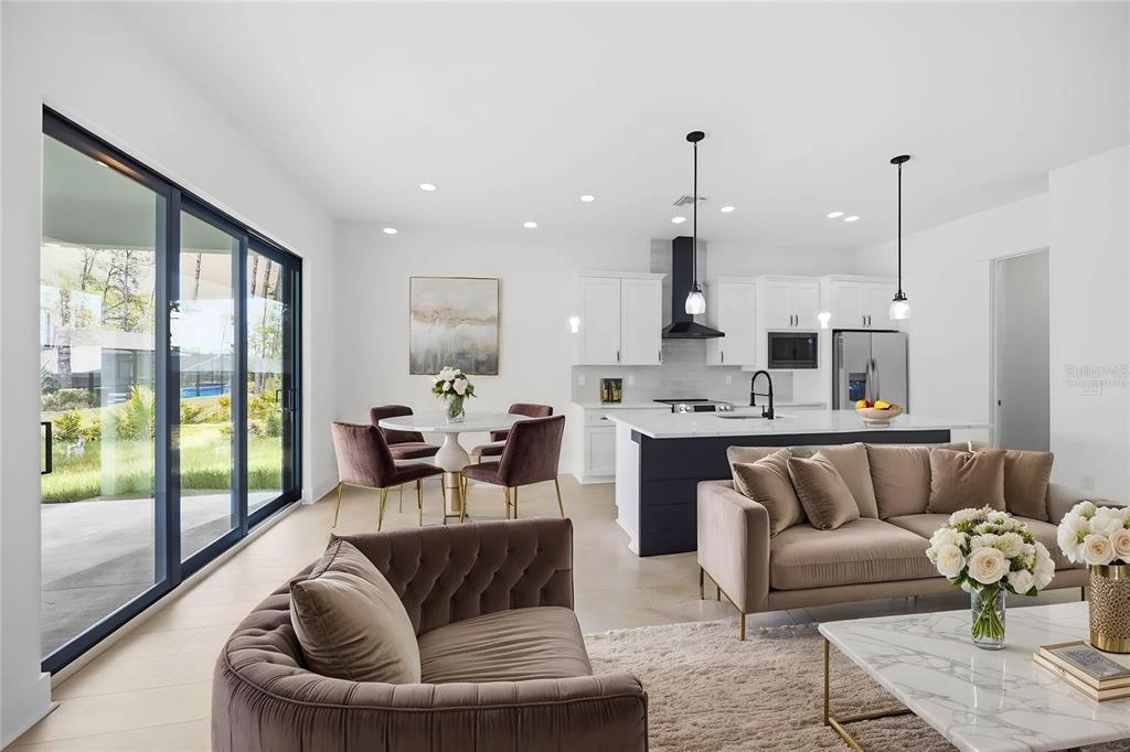 An open-concept living area features a modern kitchen, dining space, and sliding glass patio doors — 15144 FAULKNER AVENUE, PORT CHARLOTTE, FL