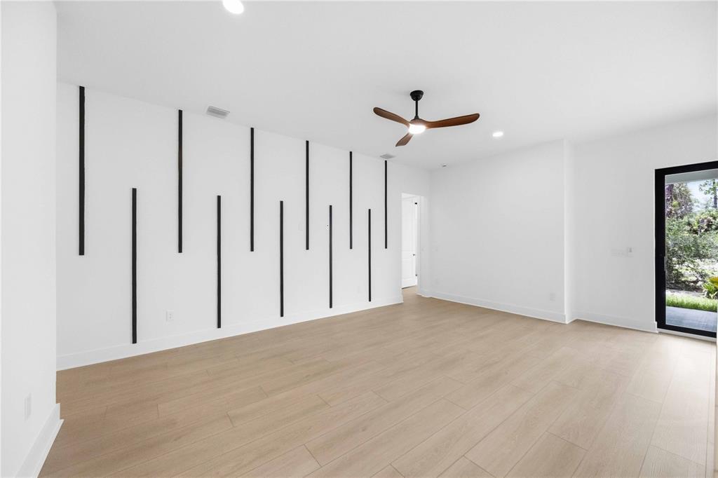 A bright room features light wood flooring, a ceiling fan, and a black-striped accent wall — 15144 FAULKNER AVENUE, PORT CHARLOTTE, FL