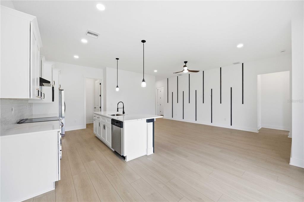 A modern kitchen with white cabinets, a central island, and a decorative black-slatted accent wall — 15144 FAULKNER AVENUE, PORT CHARLOTTE, FL