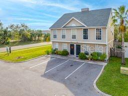 A two-story tan building with a gray roof sits beside a parking lot and lawn — 132 DOUGLAS ROAD W UNIT A, OLDSMAR, FL