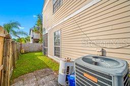 An exterior view shows a beige vinyl-sided house with an air conditioning unit and fence — 132 DOUGLAS ROAD W UNIT A, OLDSMAR, FL