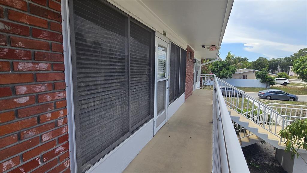 An exterior walkway with a brick wall, sliding glass doors, and a metal staircase — 3540 32ND AVENUE N UNIT 214, ST PETERSBURG, FL