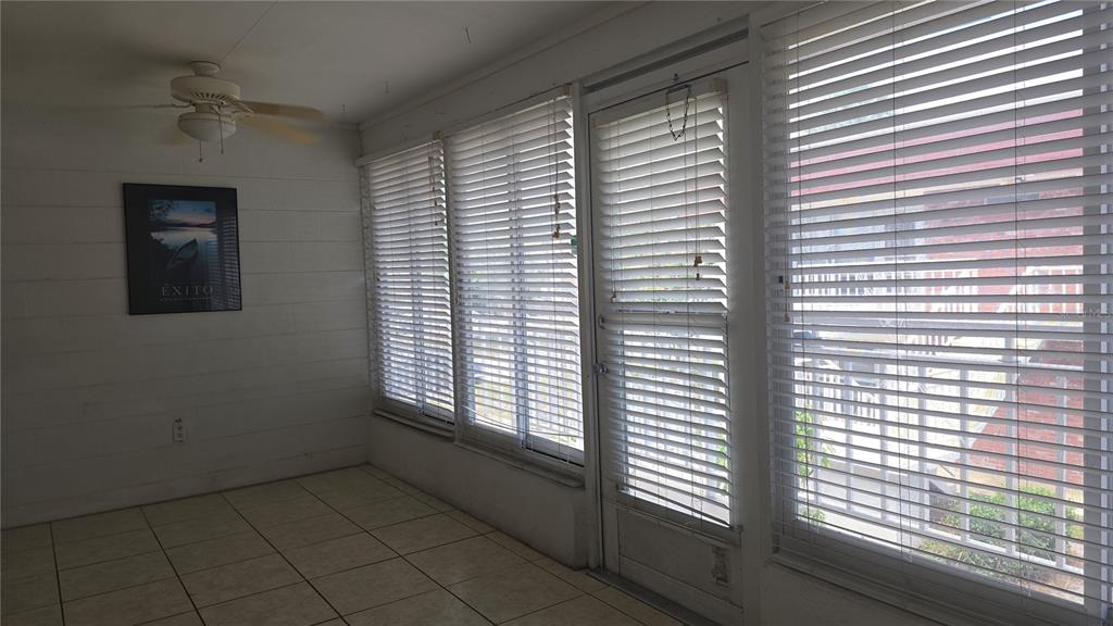 A sunroom features white paneled walls, tile flooring, a ceiling fan, and large shuttered windows — 3540 32ND AVENUE N UNIT 214, ST PETERSBURG, FL