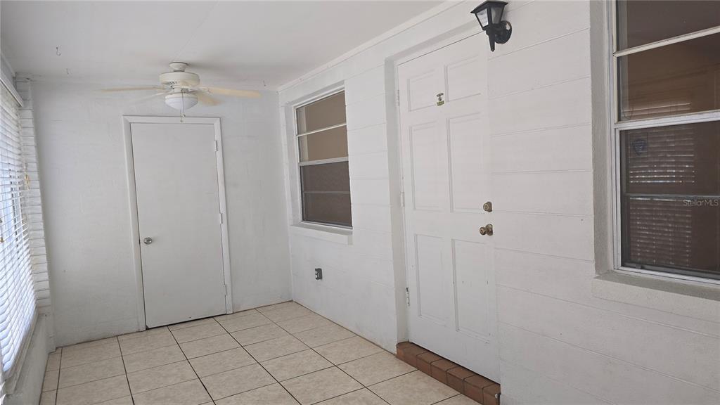 A sunroom features white block walls, tiled flooring, a ceiling fan, and two white doors — 3540 32ND AVENUE N UNIT 214, ST PETERSBURG, FL