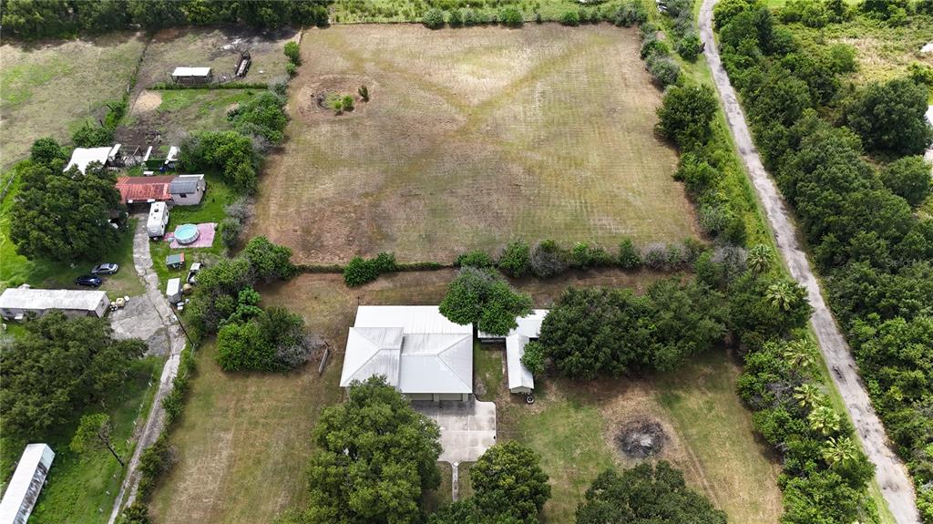 An aerial view shows a house with a metal roof, outbuildings, and a large field — 1324 CINDER LANE, KISSIMMEE, FL