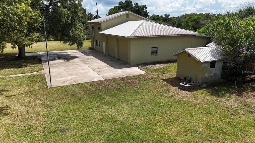 An aerial view shows a tan building with a metal roof, garage doors, and driveway — 1324 CINDER LANE, KISSIMMEE, FL