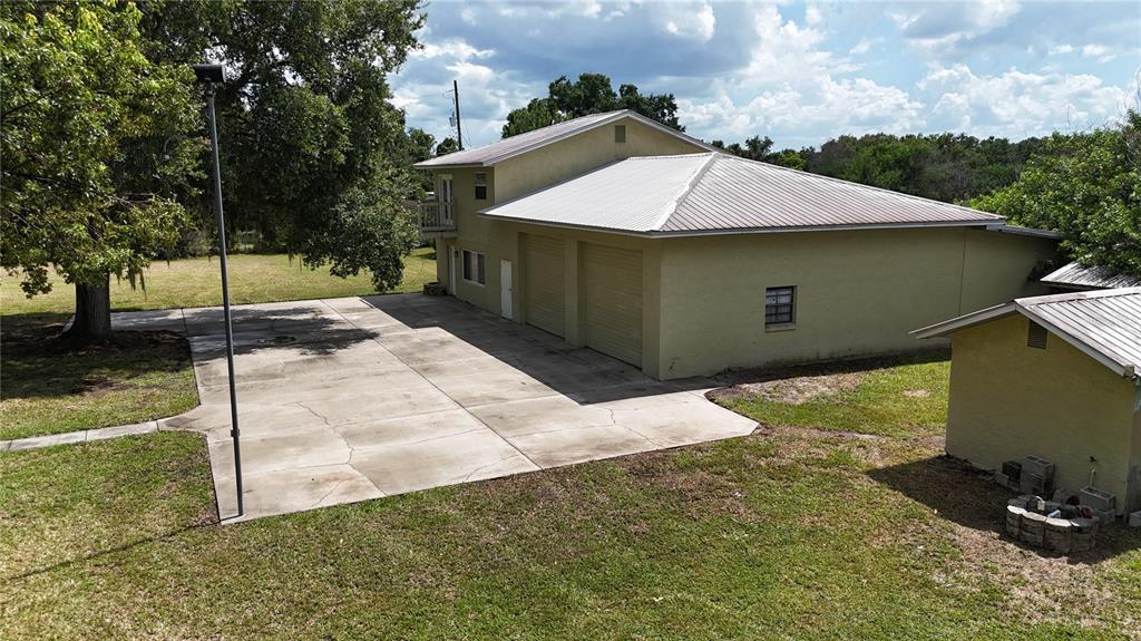 An exterior view of a two-story building with a metal roof and attached garage — 1324 CINDER LANE, KISSIMMEE, FL