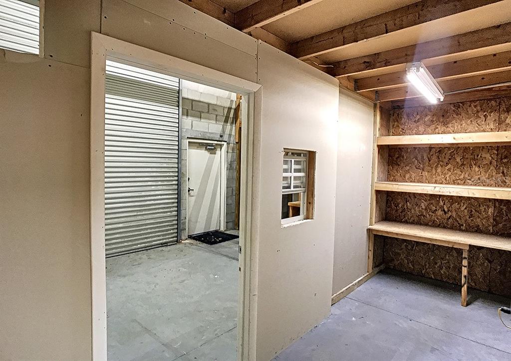 A room with drywall walls, a doorway, a small window, and wooden storage shelving — 1534-1538 TROPIC PARK DRIVE UNIT 1534-1538, SANFORD, FL
