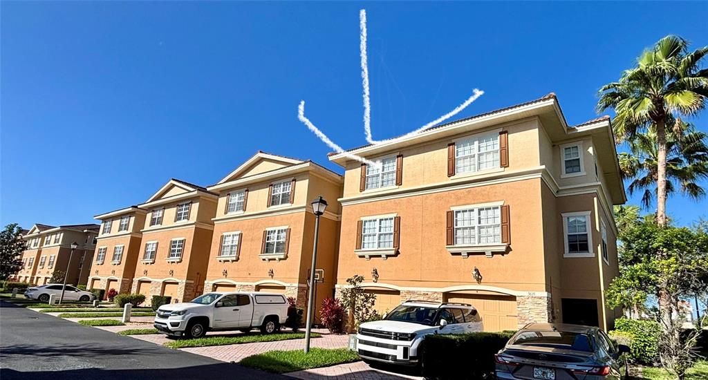 Exterior view of a multi-story tan townhouse complex with a white truck parked in front — 5633 BLACKFIN DRIVE, NEW PORT RICHEY, FL