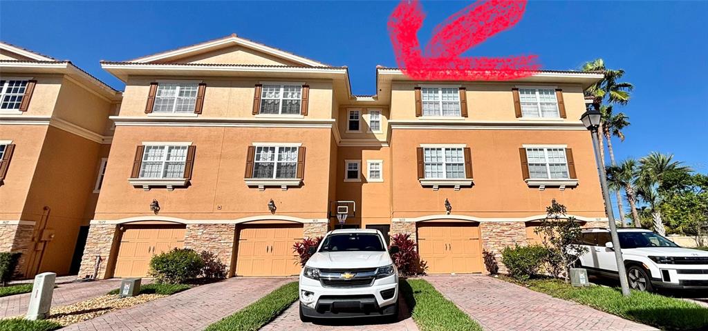 The exterior of a three-story tan townhouse complex features a white pickup truck parked in front — 5633 BLACKFIN DRIVE, NEW PORT RICHEY, FL