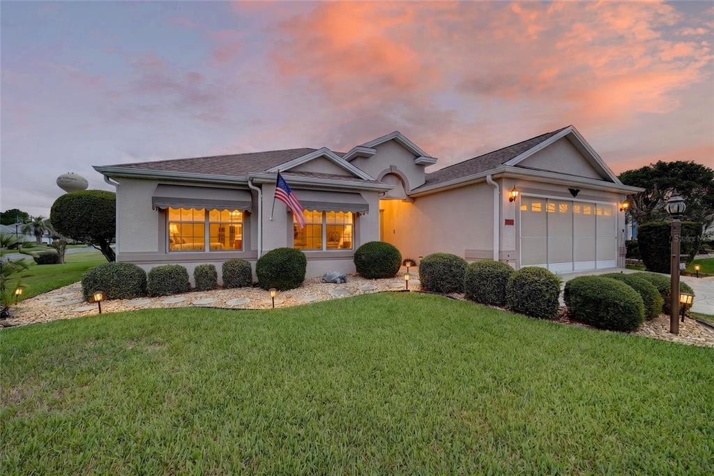 A single-story house with a beige stucco exterior, a two-car garage, and a landscaped yard — 1302 JIMENEZ COURT, THE VILLAGES, FL
