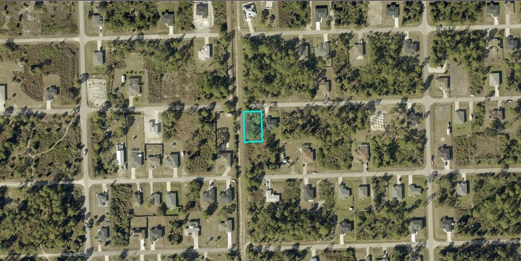 An aerial view shows a vacant, rectangular residential lot highlighted in blue within a neighborhood — 3419 71ST STREET W, LEHIGH ACRES, FL