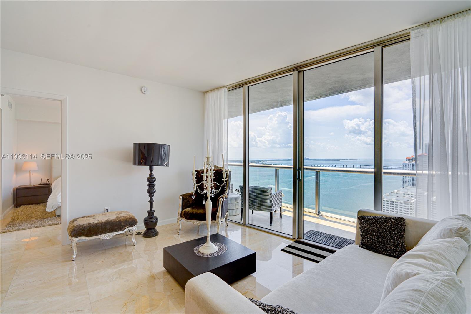 A living room features marble floors, a balcony with water views, and modern furniture — 495 Brickell Ave # 3505, Miami FL 33131, MIAMI, FL