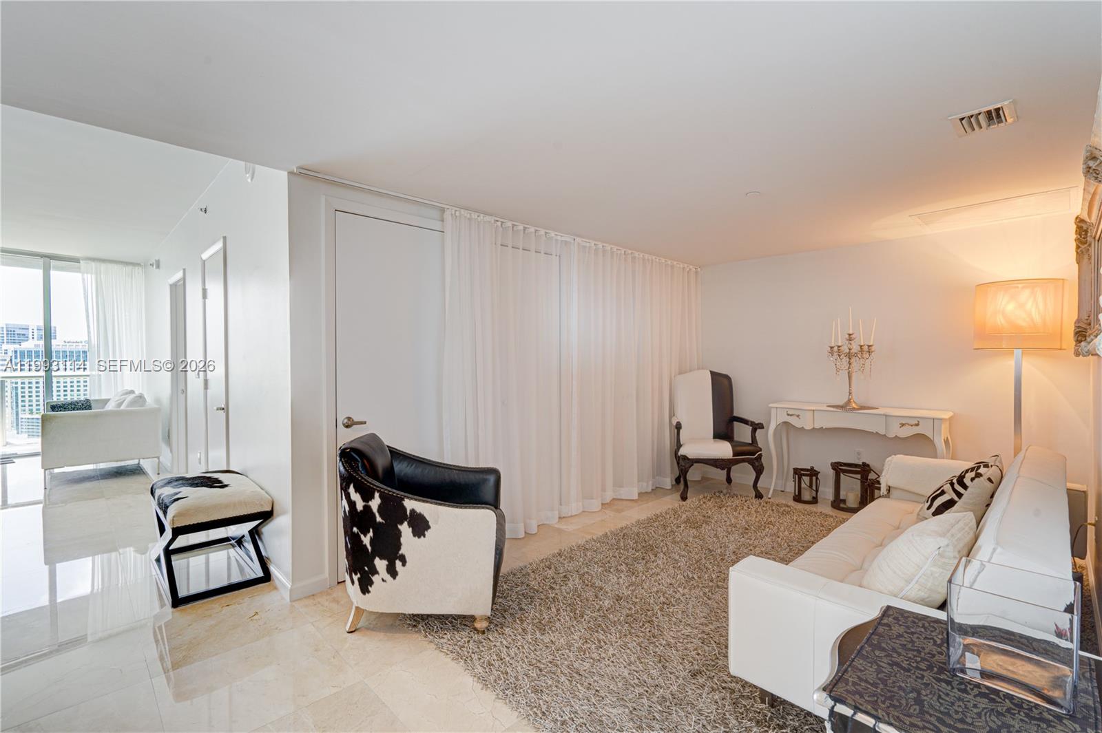 A living room features white walls, tile flooring, a cowhide chair, and a white sofa — 495 Brickell Ave # 3505, Miami FL 33131, MIAMI, FL