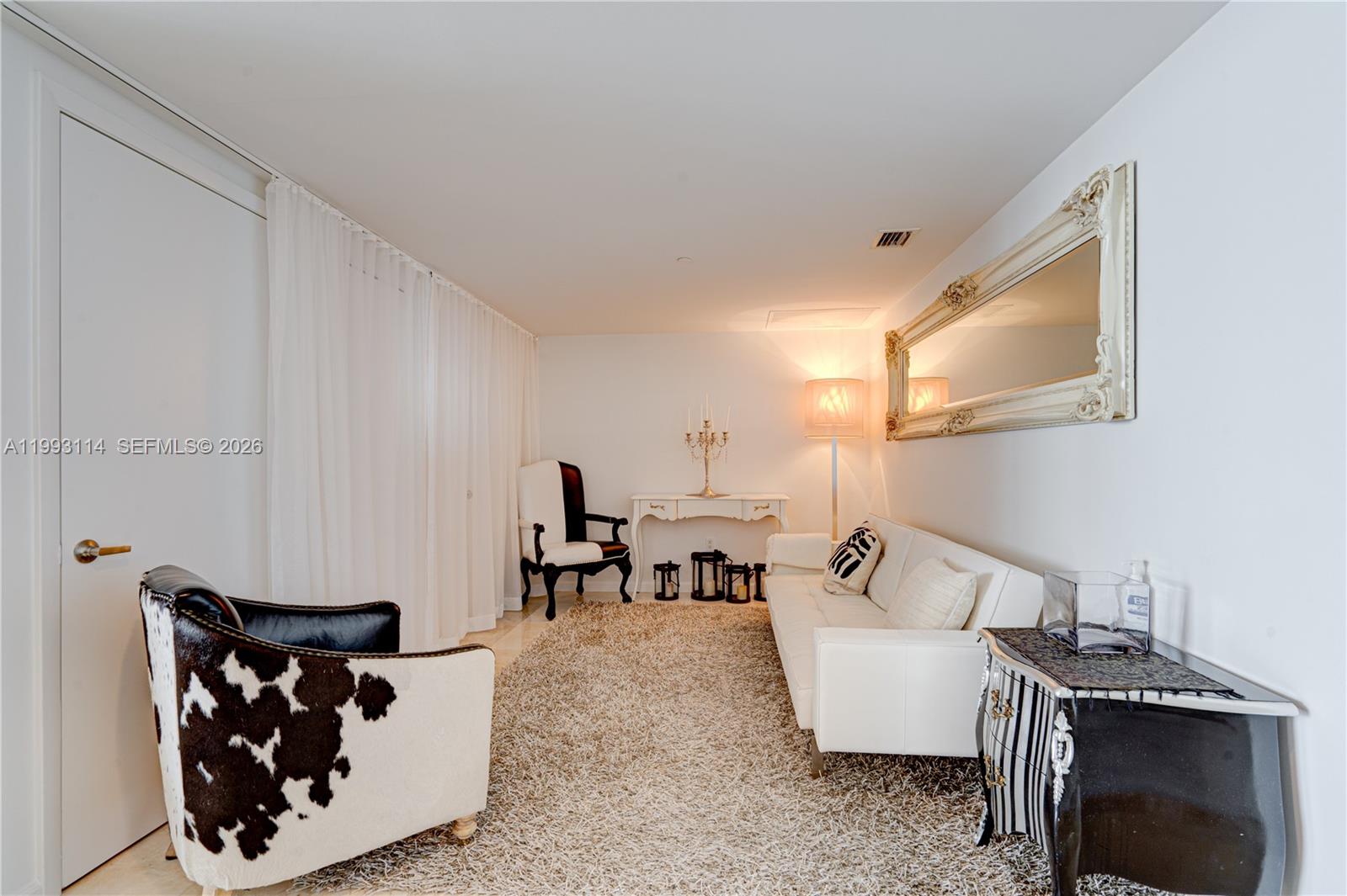 A living room features a cowhide armchair, a white sofa, and a large ornate mirror — 495 Brickell Ave # 3505, Miami FL 33131, MIAMI, FL
