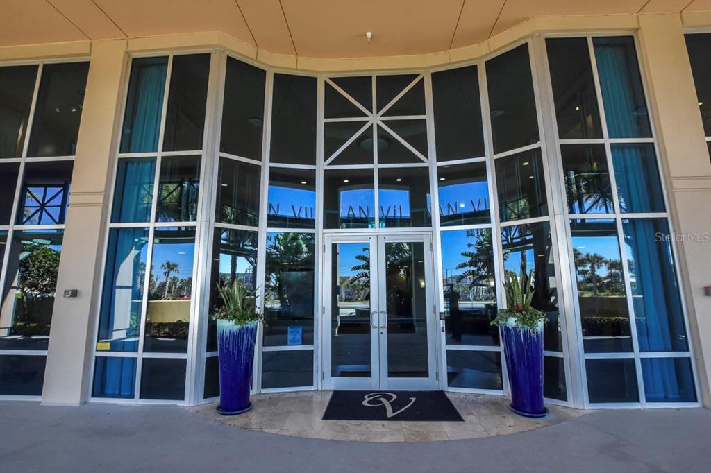 The exterior entrance of a building features glass doors, large windows, and two blue planters — 3703 S ATLANTIC AVENUE UNIT 1004, DAYTONA BEACH, FL