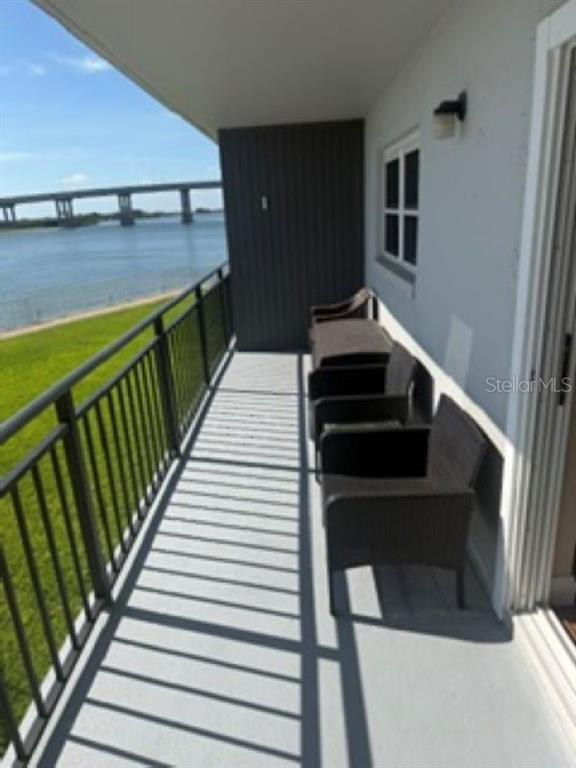 A balcony with dark wicker chairs overlooks a body of water and a distant bridge — 101 N RIVERSIDE DRIVE UNIT 2020, NEW SMYRNA BEACH, FL