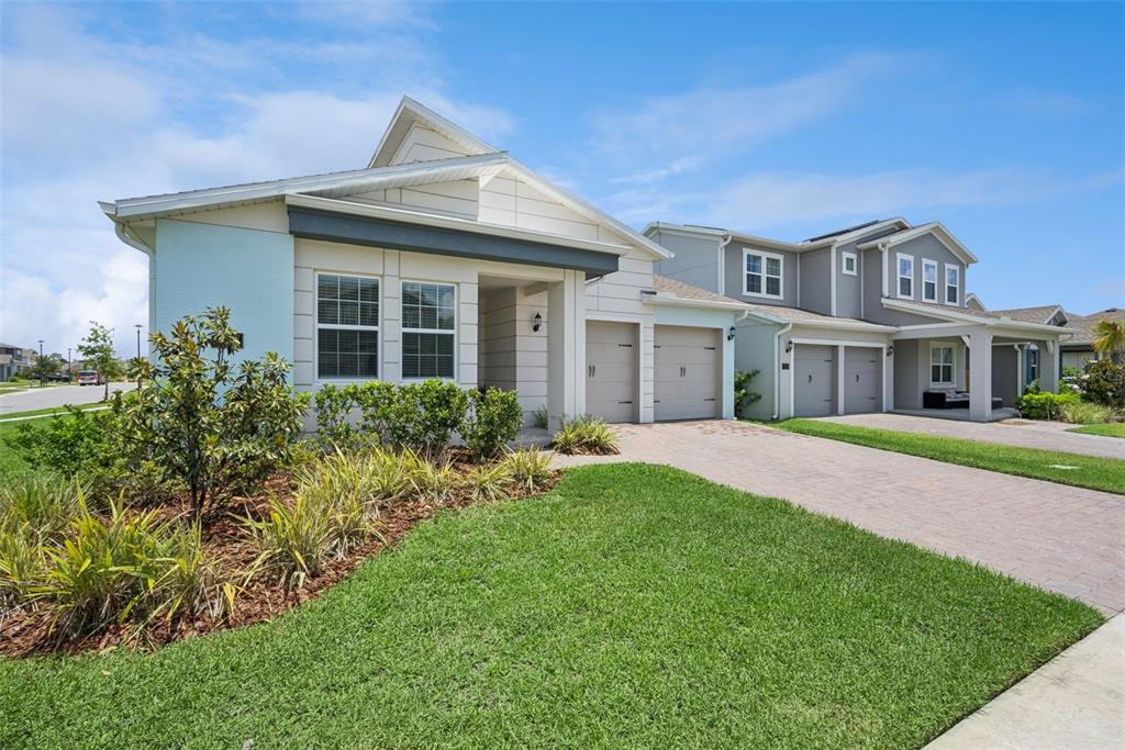 Two adjacent suburban houses with light-colored siding, paved driveways, and manicured lawns under a blue sky — 19307 BANFIELD PLACE, ORLANDO, FL